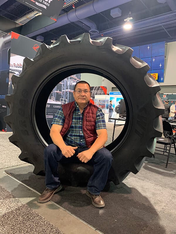 José Luis Sánchez, owner of Michoacan Auto, seated inside a tractor tire at a trade show